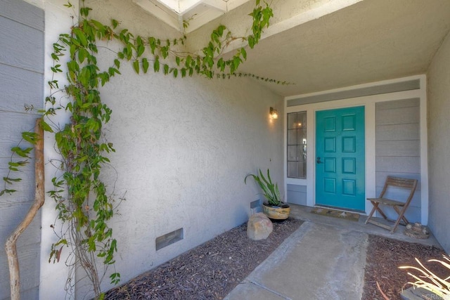 view of exterior entry featuring stucco siding and crawl space