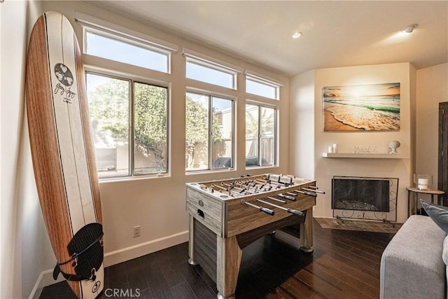 game room with dark wood finished floors, plenty of natural light, a fireplace with flush hearth, and baseboards