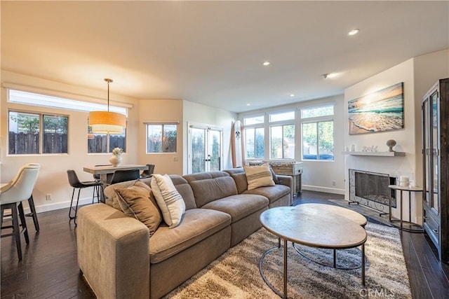 living area with recessed lighting, baseboards, a fireplace with flush hearth, and dark wood-type flooring