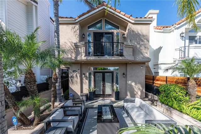 back of house with an outdoor living space, french doors, a balcony, and stucco siding