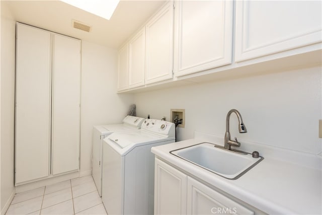 clothes washing area featuring visible vents, washer and clothes dryer, a sink, cabinet space, and light tile patterned flooring