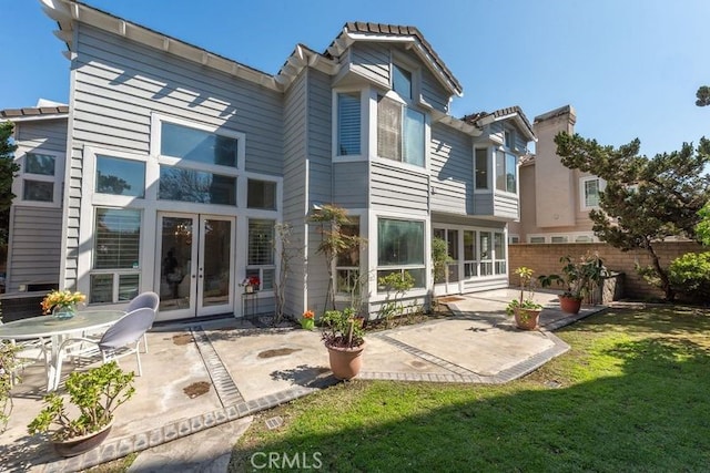 back of property with a lawn, french doors, a patio, and fence