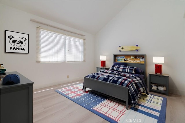 bedroom with wood finished floors, baseboards, and vaulted ceiling