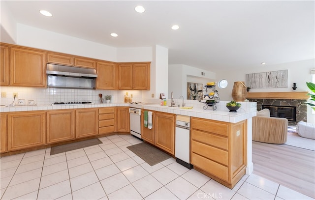 kitchen with under cabinet range hood, gas cooktop, a peninsula, white dishwasher, and tile counters