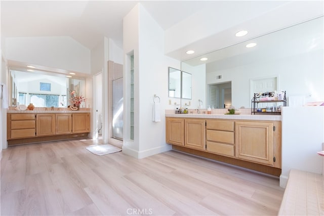 full bath featuring lofted ceiling, two vanities, wood finished floors, and a shower stall