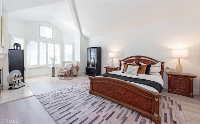 bedroom with high vaulted ceiling, baseboards, and wood finished floors