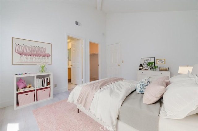 bedroom with beamed ceiling, visible vents, high vaulted ceiling, a walk in closet, and connected bathroom