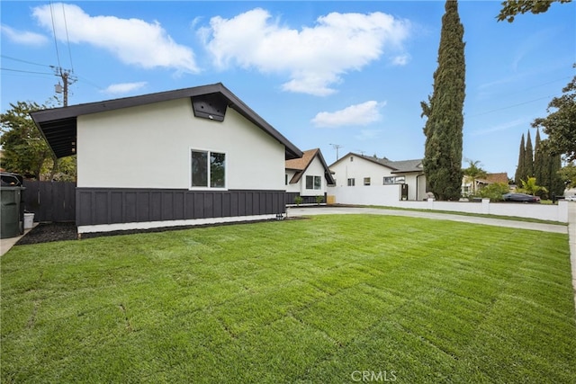 view of property exterior featuring a yard, fence, and stucco siding