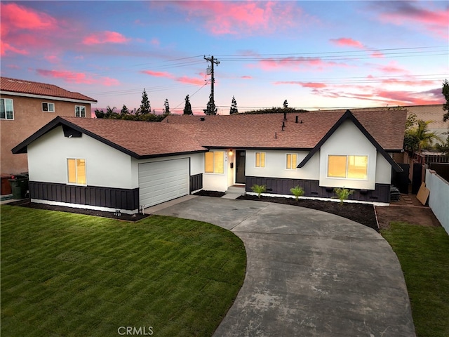 view of front facade featuring stucco siding, fence, a yard, concrete driveway, and a garage