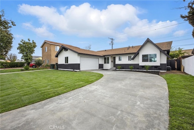 view of front of property featuring a front lawn, fence, concrete driveway, stucco siding, and an attached garage