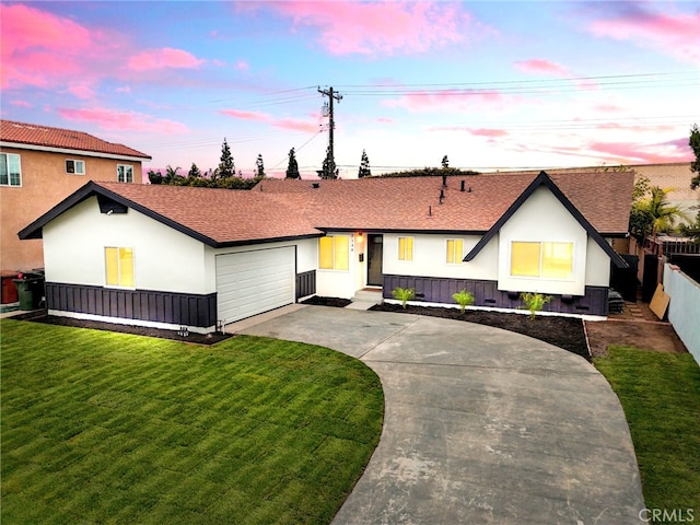 view of front of property featuring stucco siding, a lawn, fence, concrete driveway, and an attached garage