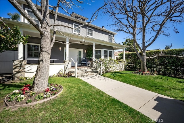 american foursquare style home featuring a front lawn, fence, and covered porch