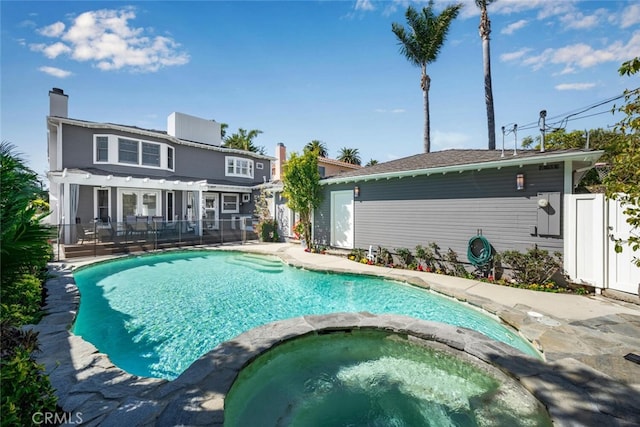 view of pool featuring a patio, fence, and a pool with connected hot tub