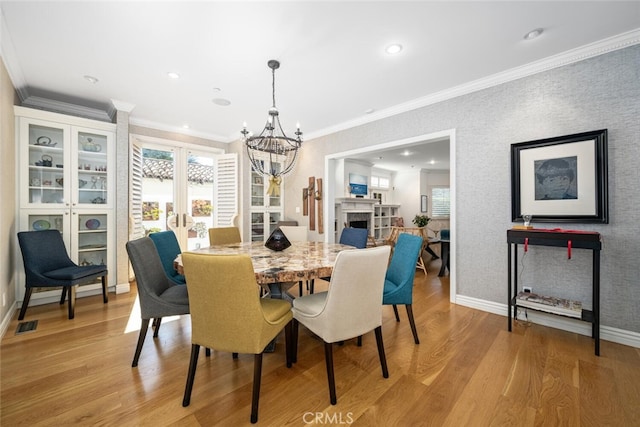 dining space featuring a fireplace, a healthy amount of sunlight, light wood-type flooring, and baseboards