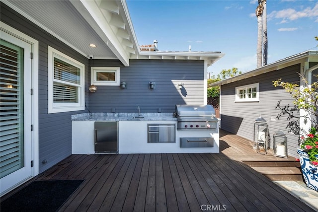 deck featuring exterior kitchen, area for grilling, and a sink