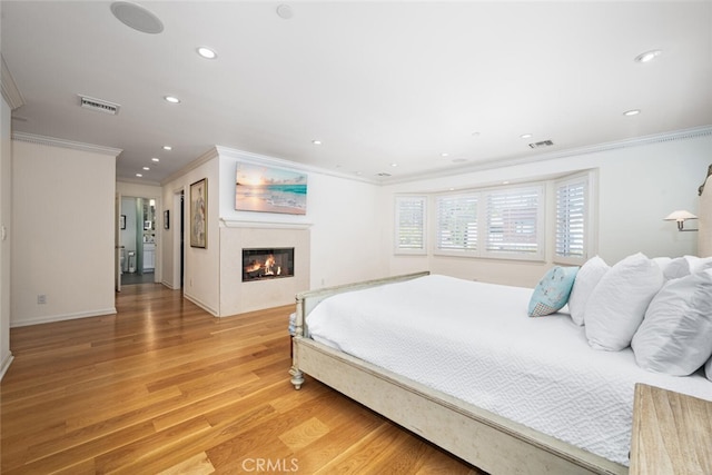 bedroom featuring recessed lighting, visible vents, light wood-style floors, and a glass covered fireplace