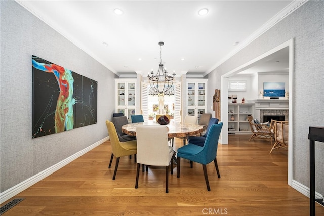 dining room with a fireplace, crown molding, wood finished floors, and baseboards