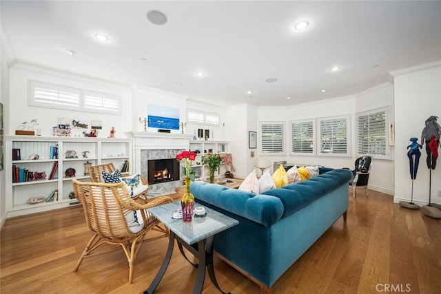 living area featuring recessed lighting, ornamental molding, a fireplace, and wood finished floors