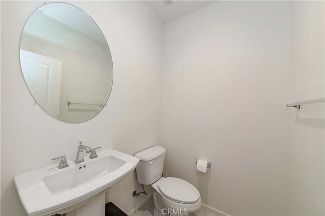 bathroom featuring toilet, baseboards, and a sink