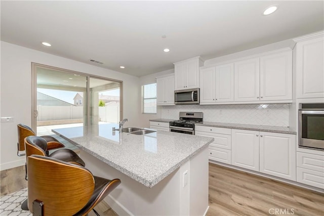 kitchen with visible vents, a sink, light wood-style floors, appliances with stainless steel finishes, and white cabinets