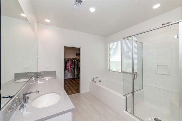 full bath with a bath, a shower stall, double vanity, and a sink