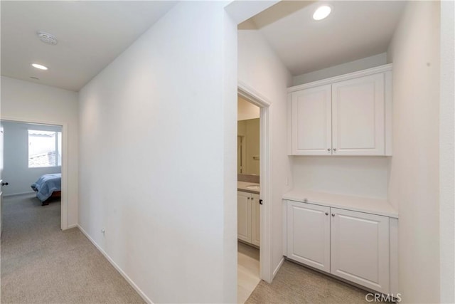 hallway featuring recessed lighting, light colored carpet, and baseboards