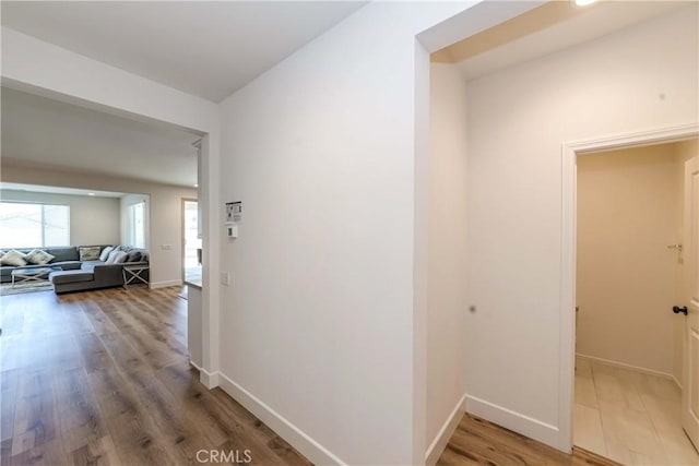 corridor with light wood-type flooring and baseboards