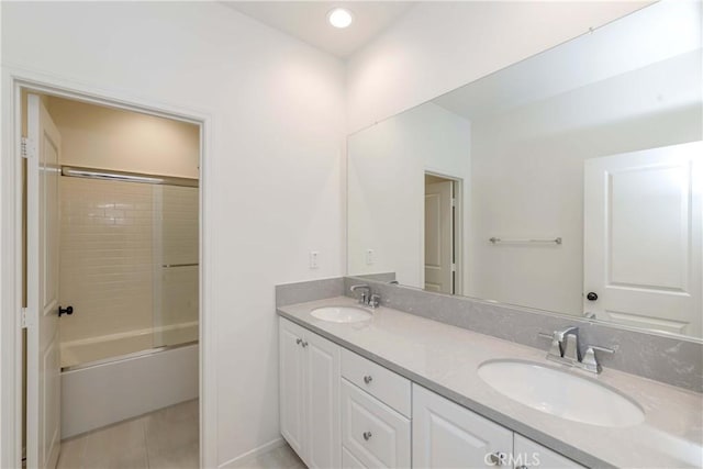 full bathroom featuring tile patterned flooring, double vanity, enclosed tub / shower combo, and a sink