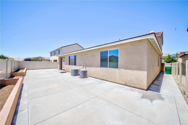 rear view of house featuring a fenced backyard, stucco siding, and a patio