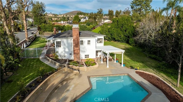 rear view of house featuring fence, stucco siding, a yard, an outdoor pool, and a patio