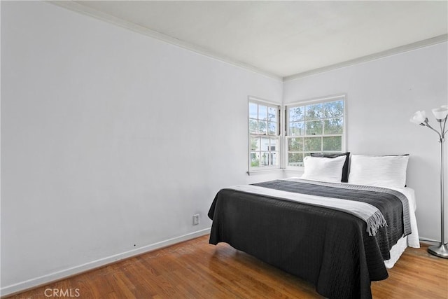 bedroom featuring crown molding, wood finished floors, and baseboards