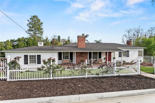 ranch-style home with a fenced front yard, covered porch, and a chimney