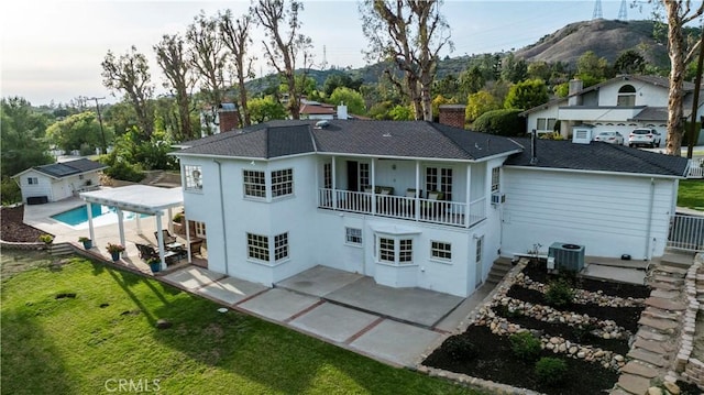 back of house featuring cooling unit, a yard, a balcony, a chimney, and a patio area