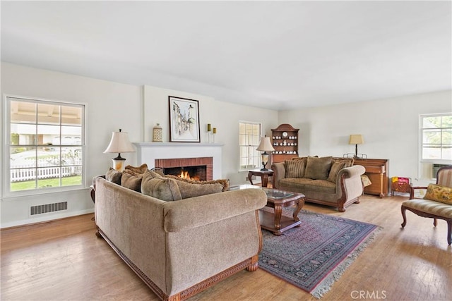 living area featuring visible vents, baseboards, light wood-style floors, and a fireplace