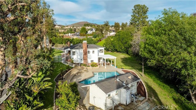 rear view of house with an outdoor pool, a yard, a mountain view, and a patio area