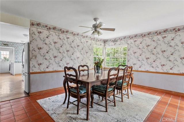 tiled dining space with a wealth of natural light, wainscoting, wallpapered walls, and independent washer and dryer