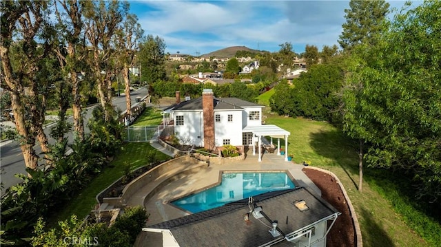 back of house featuring a lawn, a patio, fence, a mountain view, and a fenced in pool