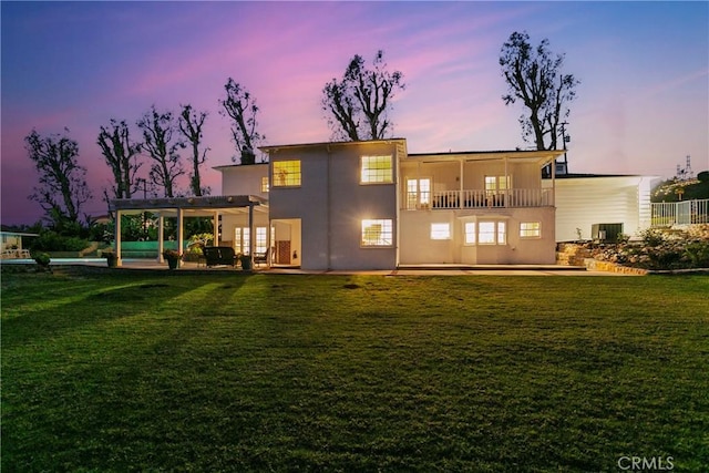 back of property featuring central air condition unit, a lawn, stucco siding, a balcony, and a patio