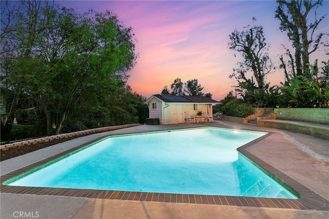 outdoor pool with an outbuilding, a patio area, and an exterior structure