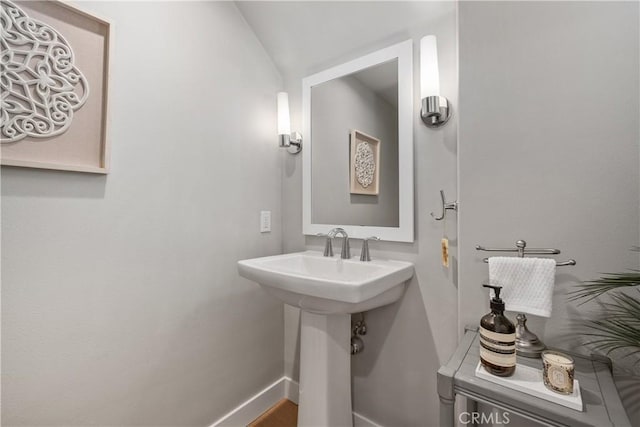 bathroom featuring lofted ceiling, baseboards, and a sink