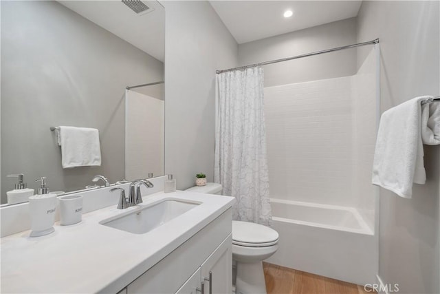 bathroom with visible vents, toilet, wood finished floors, shower / bath combination with curtain, and vanity