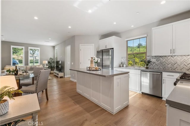 kitchen featuring open floor plan, white cabinetry, stainless steel appliances, and light wood-type flooring