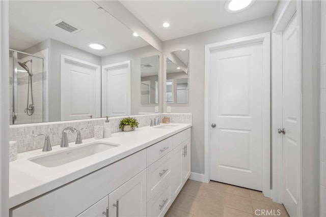 full bath with visible vents, backsplash, a stall shower, and a sink