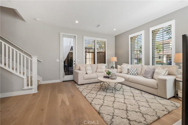 living area featuring visible vents, baseboards, stairway, recessed lighting, and wood finished floors