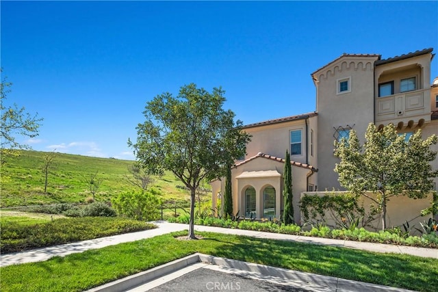 view of front of property with stucco siding, uncovered parking, and a tiled roof