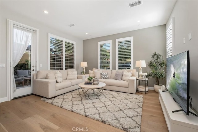 living area with visible vents, recessed lighting, light wood-type flooring, and baseboards