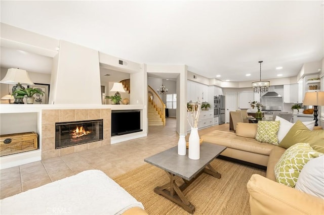 living area featuring visible vents, recessed lighting, stairway, a chandelier, and a tile fireplace