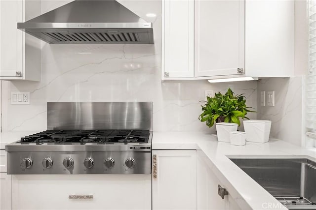 kitchen featuring white cabinetry, extractor fan, stainless steel gas stovetop, and a sink