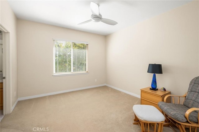 living area with ceiling fan, baseboards, and light carpet