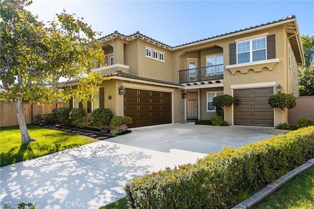 mediterranean / spanish-style home with stucco siding, an attached garage, and fence